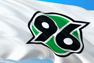 Flagge des Fußballclubs Hannover 96 vor blauem Hintergrund.